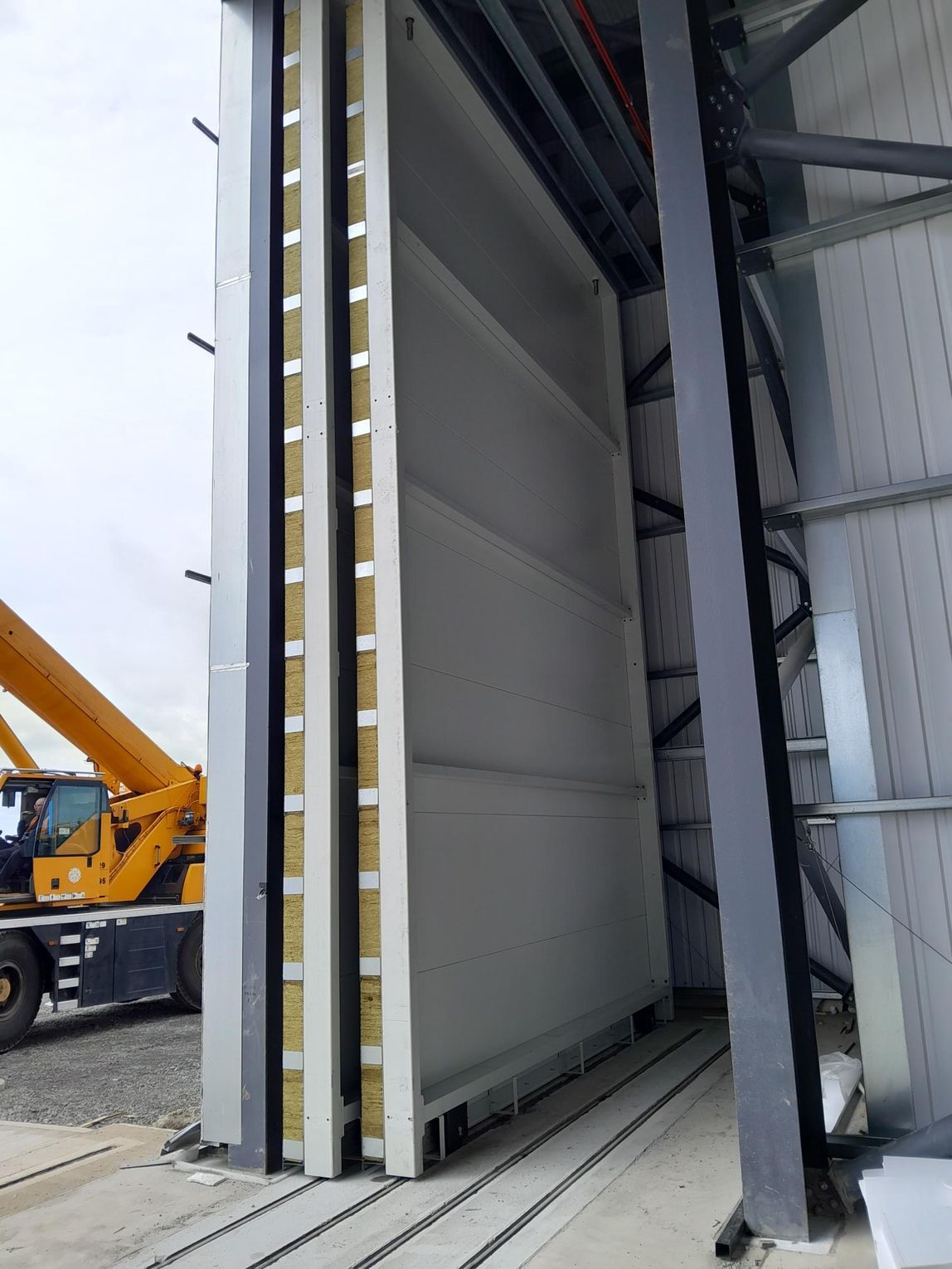 A yellow crane is parked next to a large door