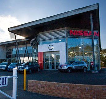 A nissan car dealership with cars parked in front of it