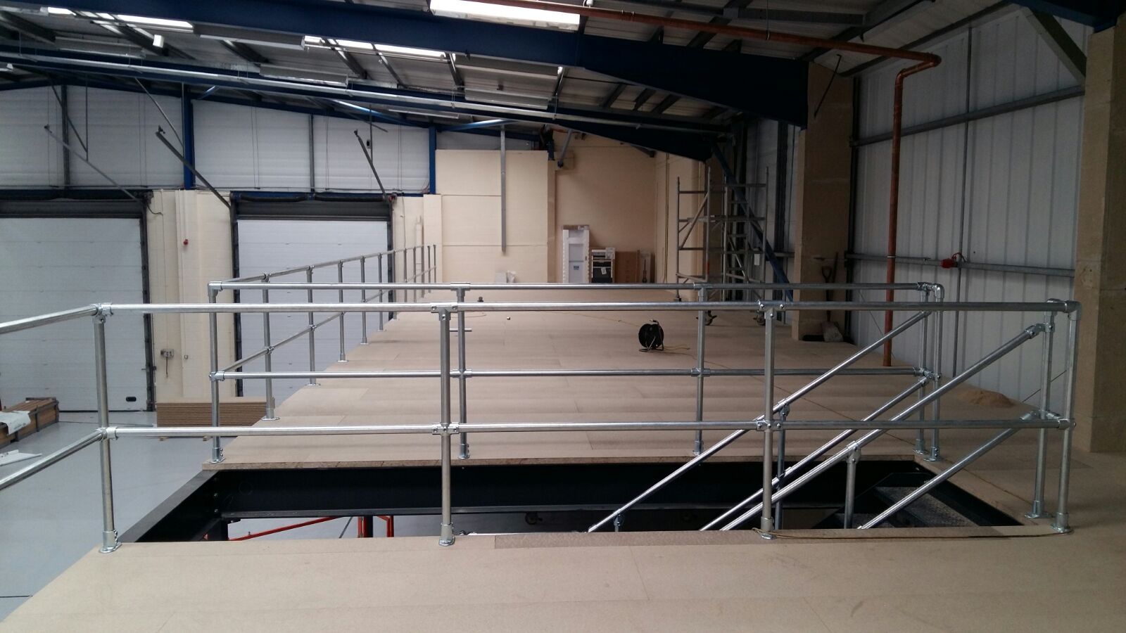 An empty warehouse with a metal railing and stairs