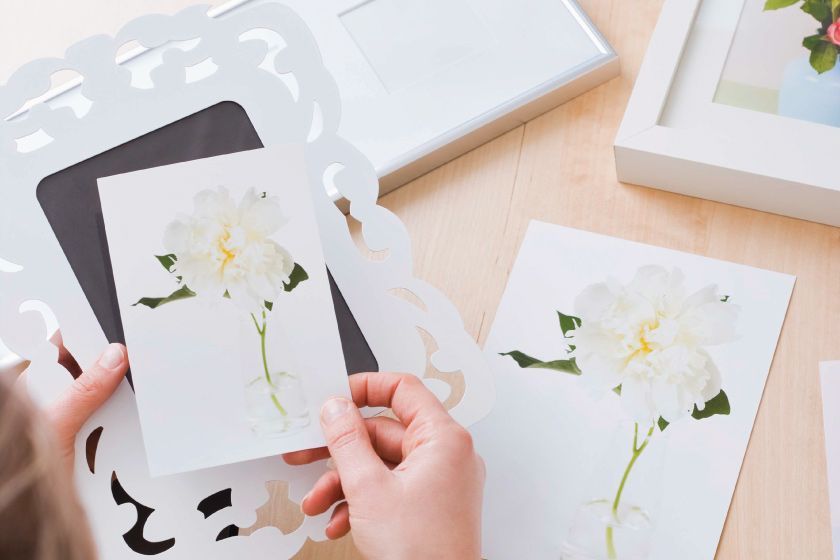 Une personne tenant un cadre et une photo avec des fleurs dessus