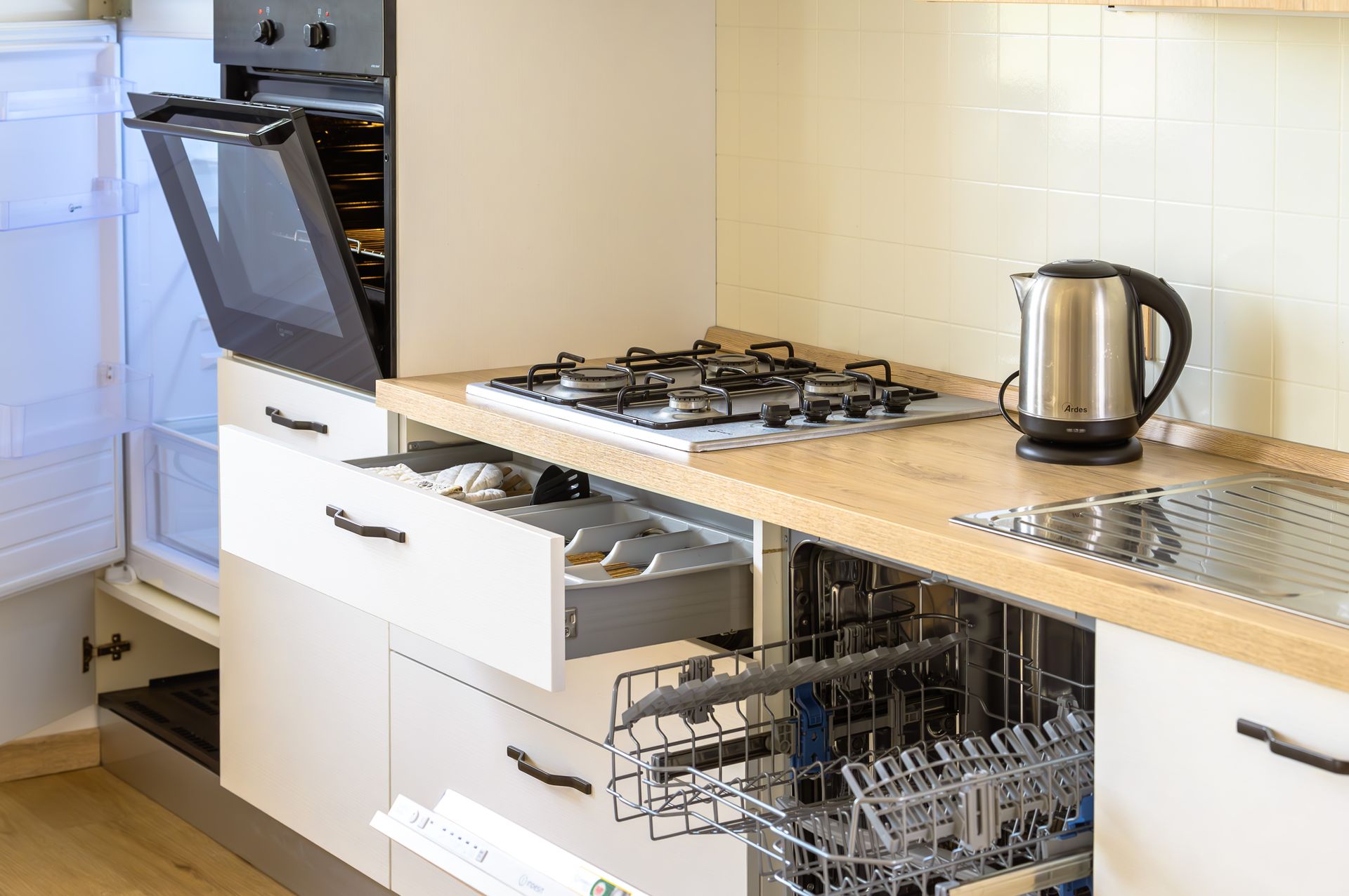 Cucina con forno a vista, lavastoviglie e cassetti; fornello a gas, bollitore elettrico e lavello sul piano di lavoro.