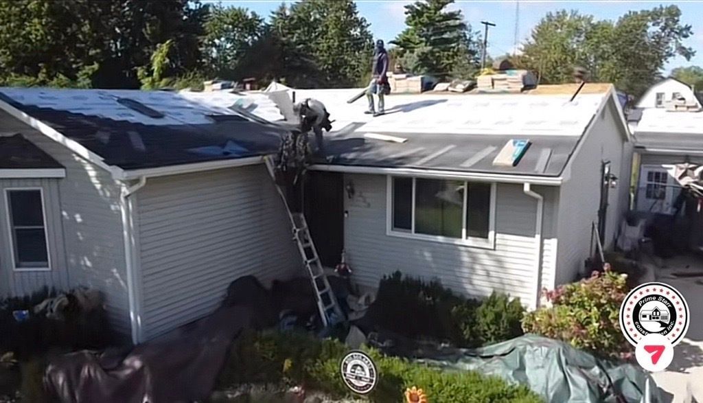 Two-story house with roof damage, a ladder against it, and workers inspecting the roof