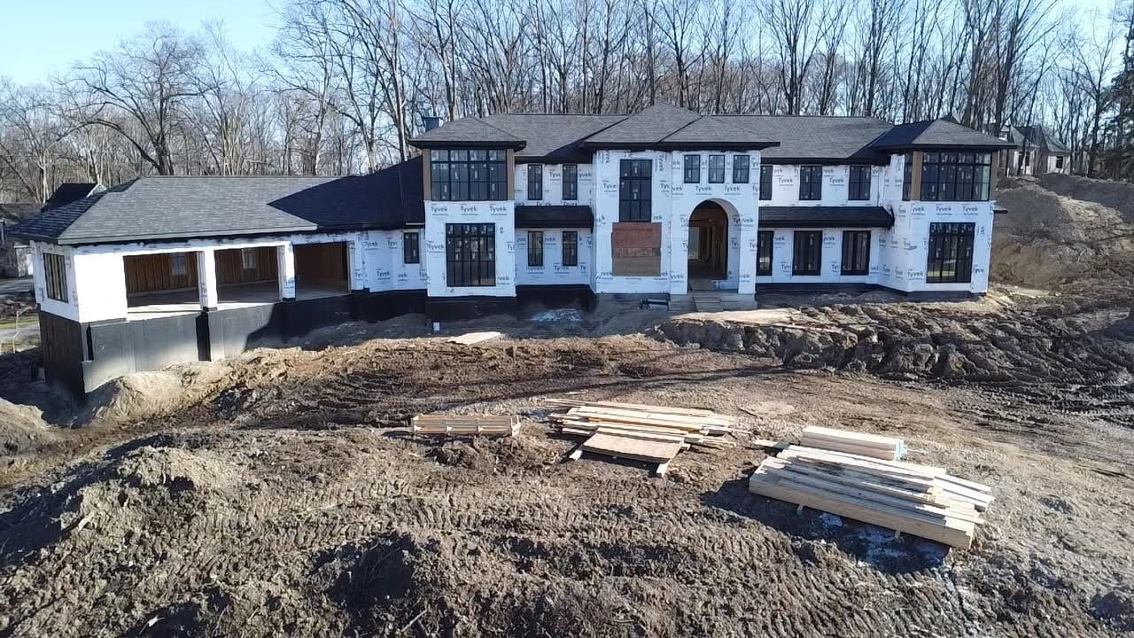 A large house is being built in the middle of a dirt field.