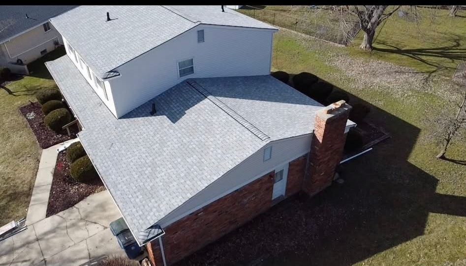 An aerial view of a house with a gray roof and a chimney. An aerial view of a house with a gray roof and a chimney.
