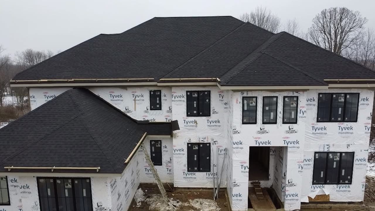 A large house with a black roof is being built.