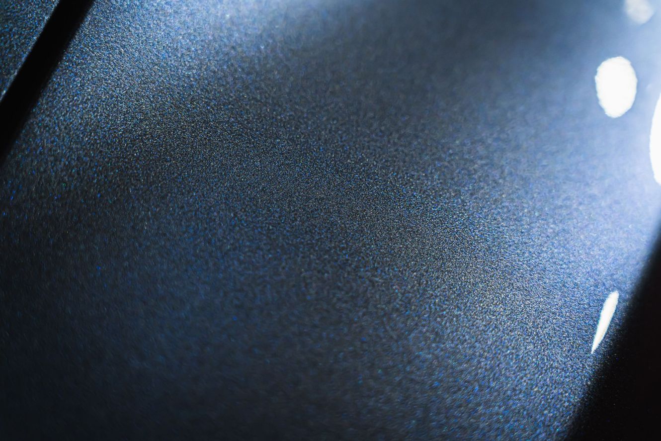 Close-up of metallic blue car paint with subtle glitter effect, reflecting light.