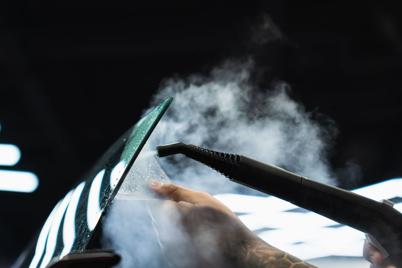 Hand steaming a curved, black object; steam billows.