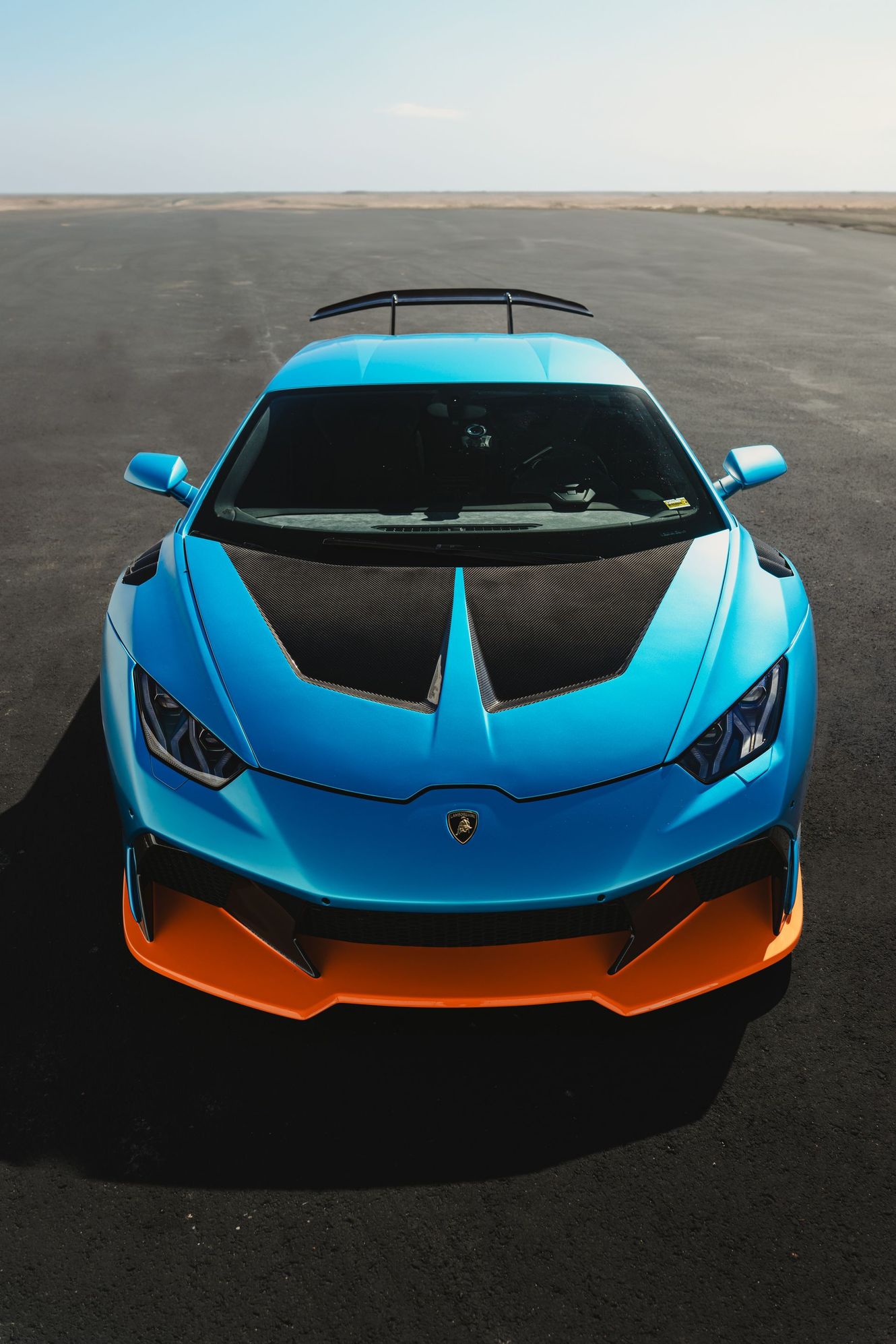 Blue Lamborghini race car with orange accents on a black asphalt track.