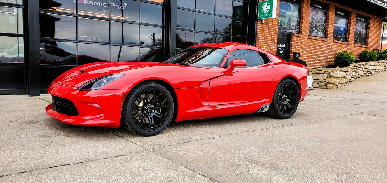 Red sports car parked in front of a building with black doors.
