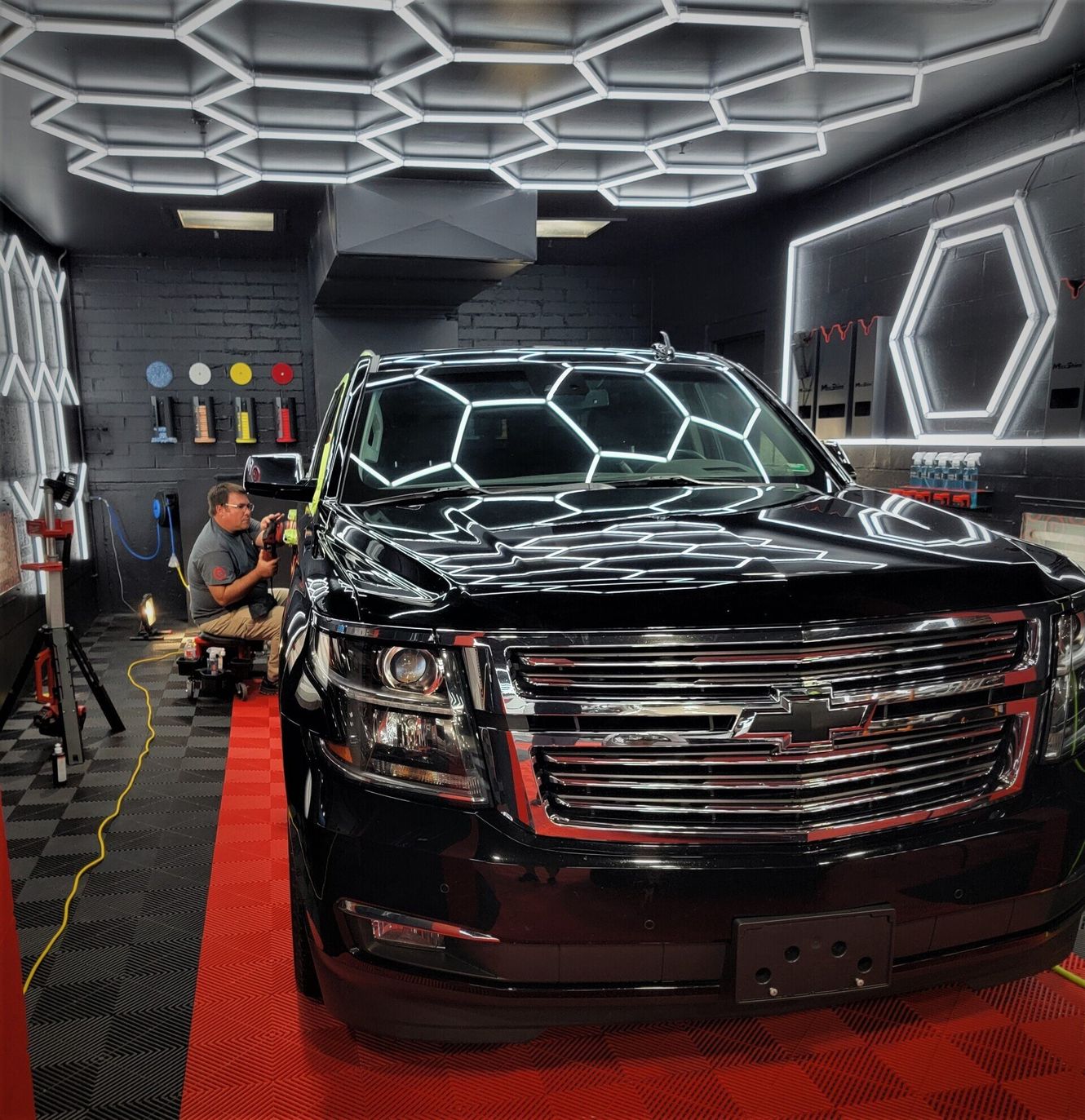 A black suv is parked in a garage with lights on the ceiling