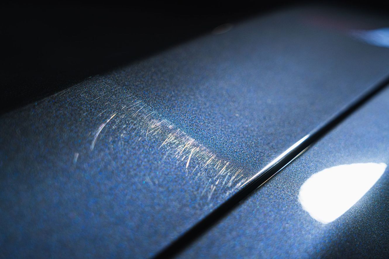 Scratches on a blue metallic car surface, with a visible line separating the panels.