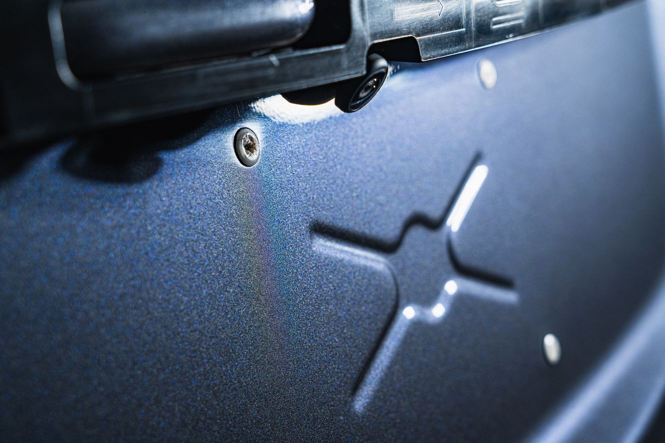 Close-up of textured, dark blue metal panel with a stylized 