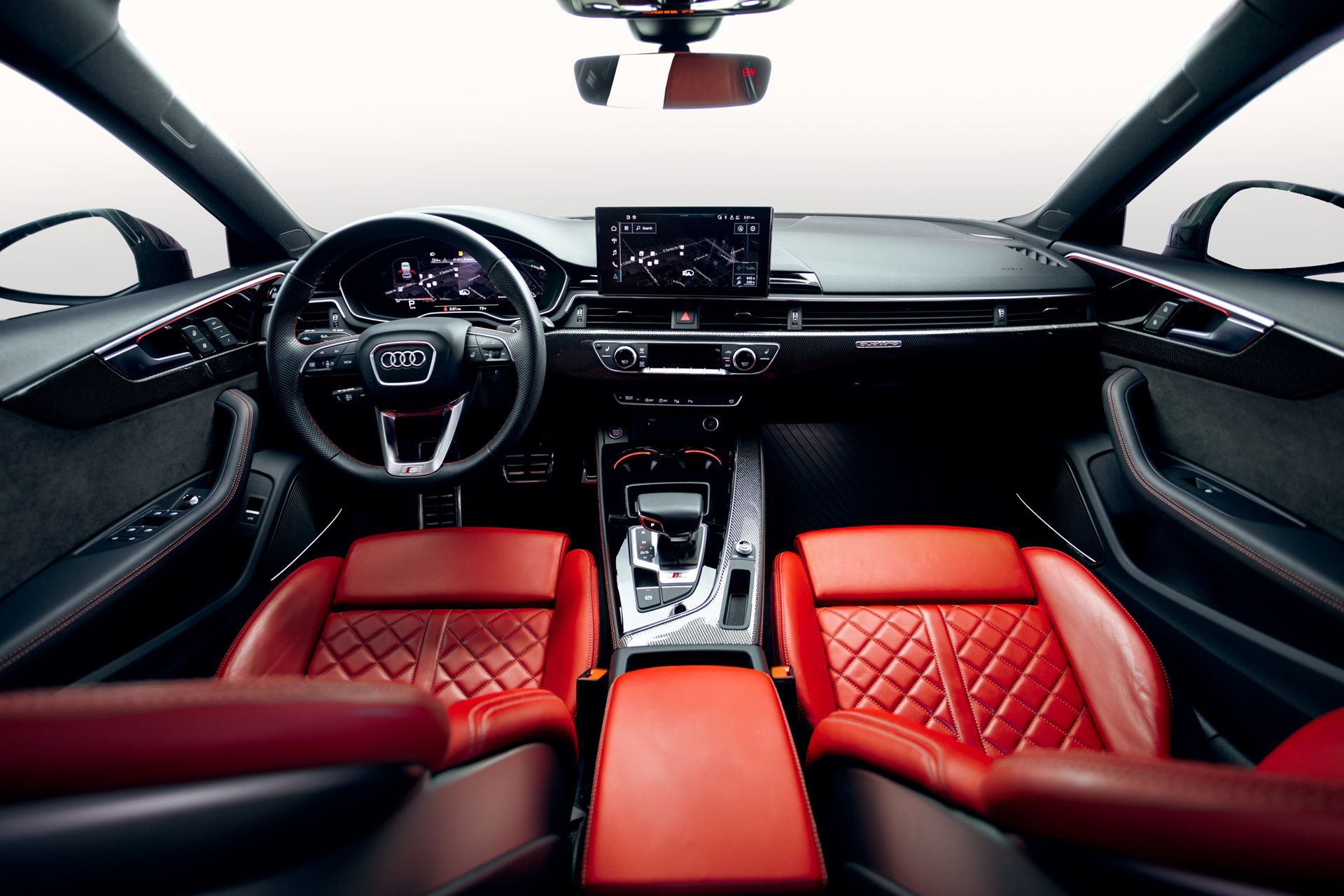 Interior of a red and black Audi, focusing on the dashboard, steering wheel, and leather seats.