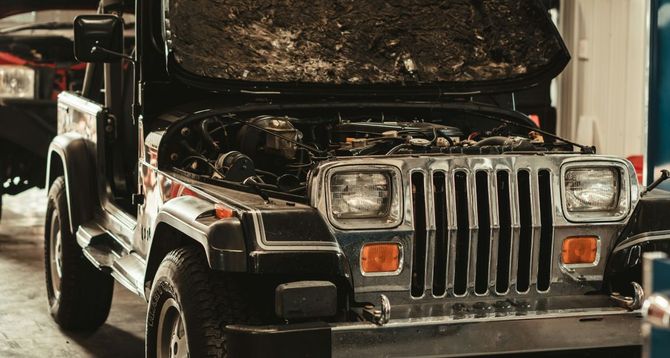Black vintage Jeep with hood open in a garage, front grille and headlights visible. | Hunts Point Service Station
