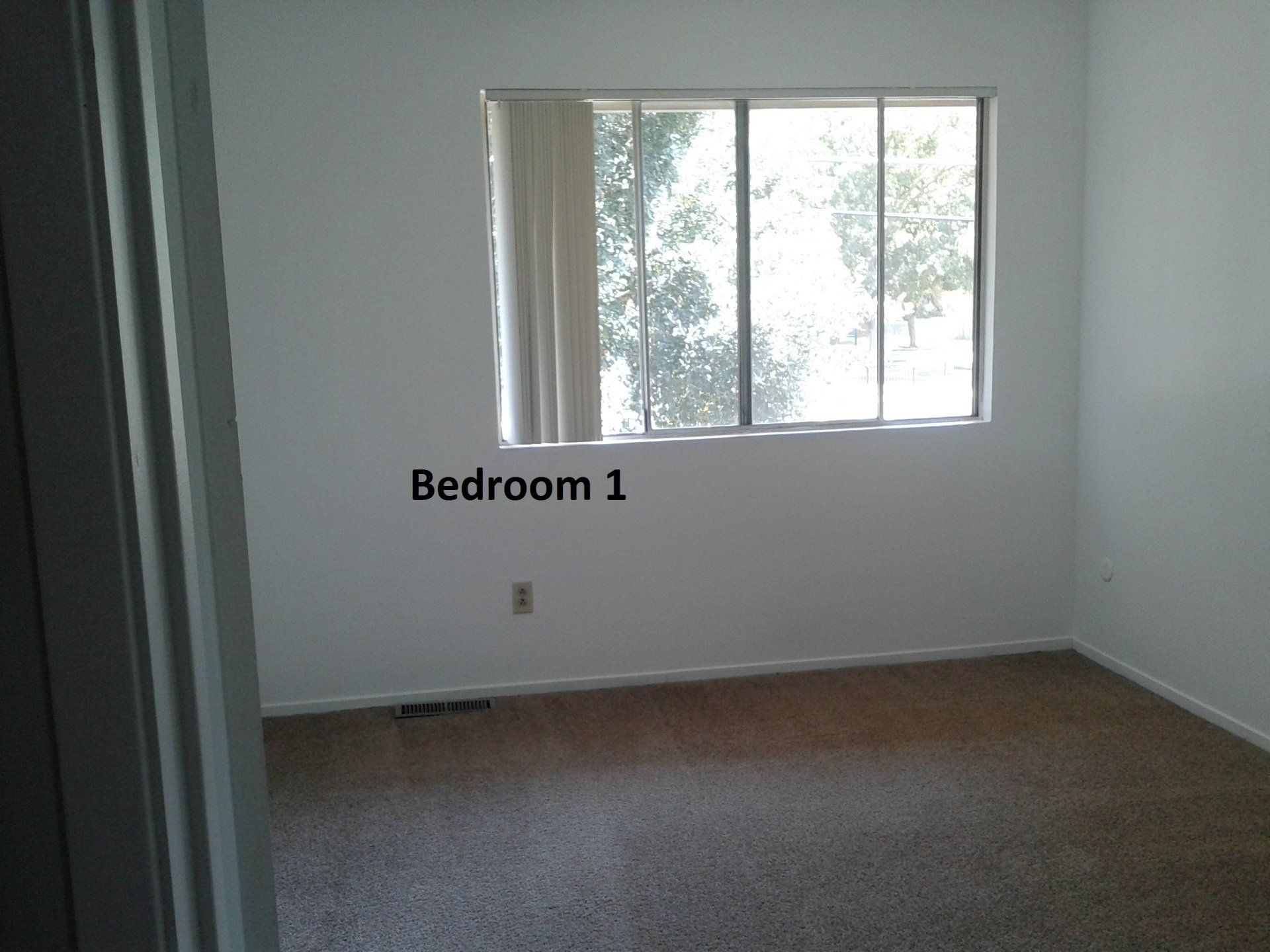 Bedroom 1 with beige carpet and window