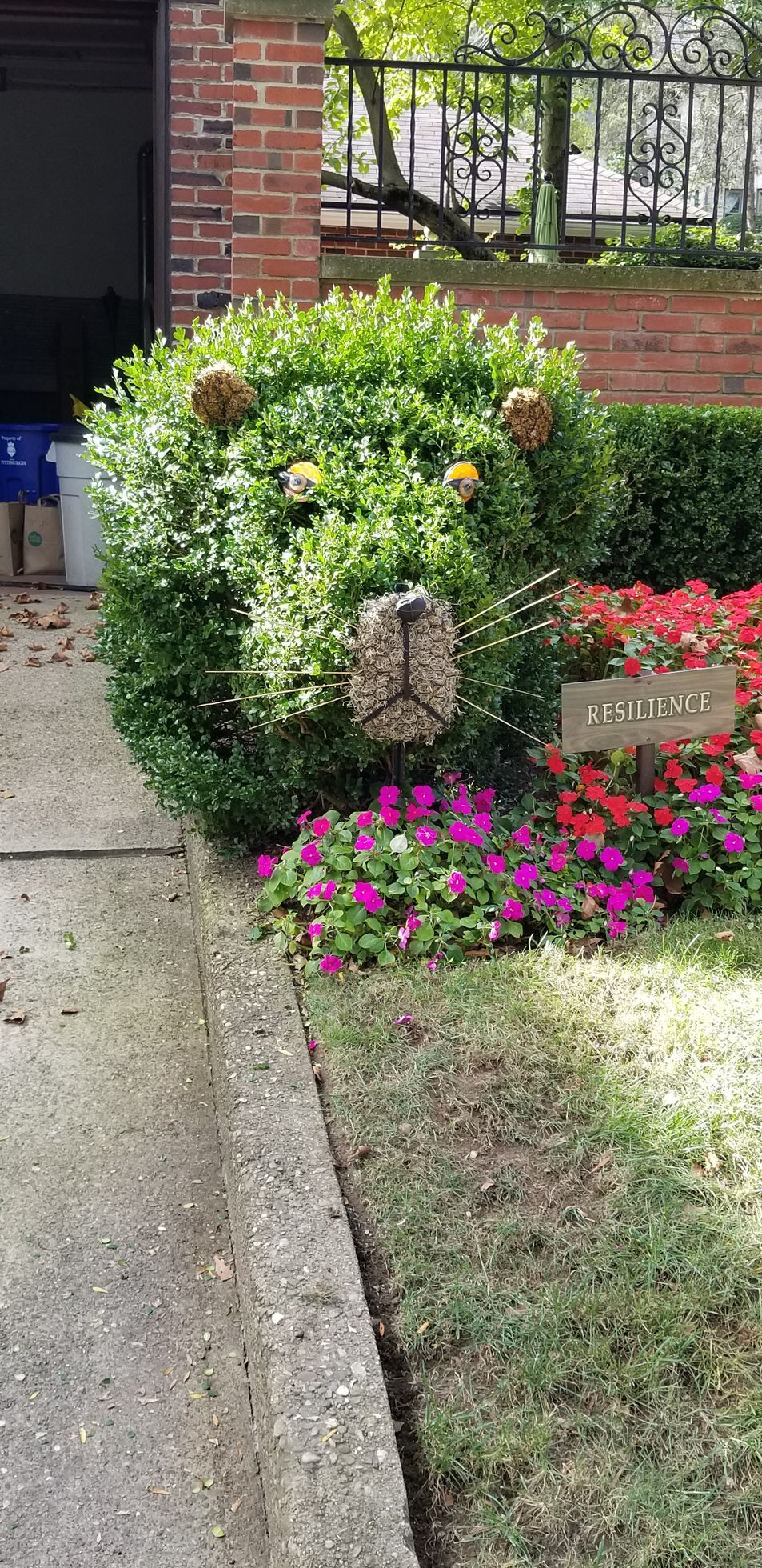A garden with flowers and bushes in front of a brick building.