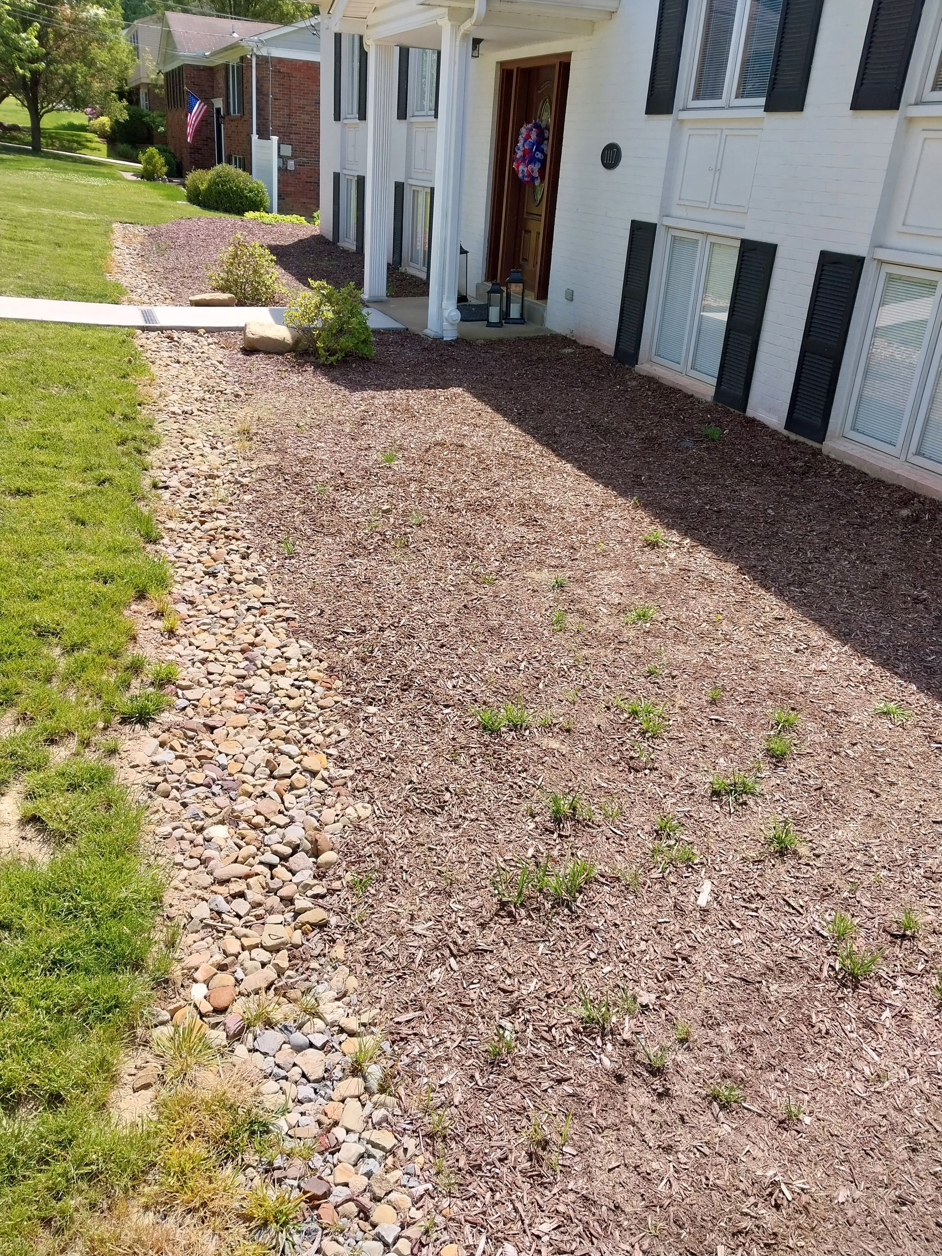 A white house with a gravel driveway in front of it.