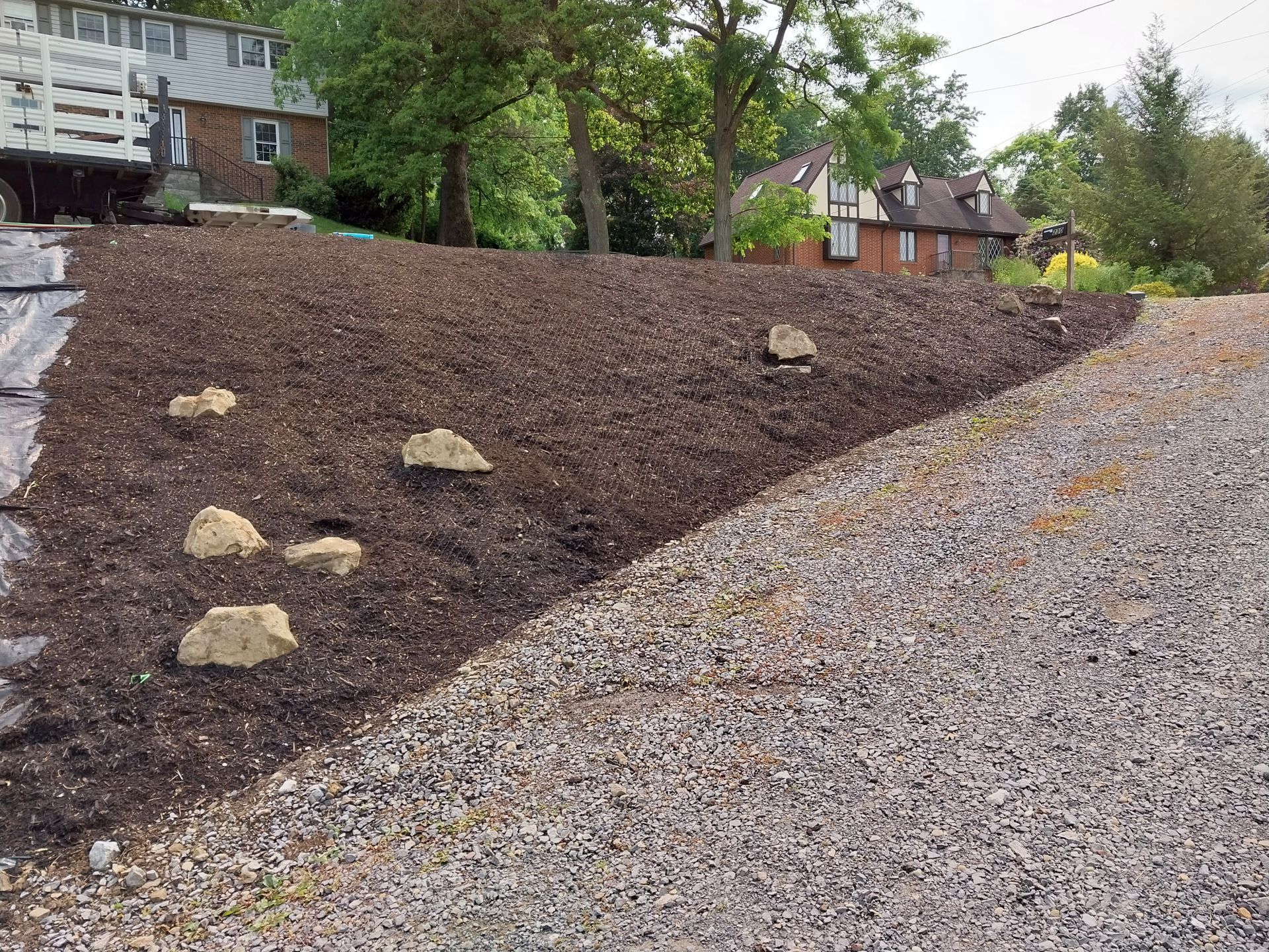 A pile of gravel is sitting on top of a hill next to a house.