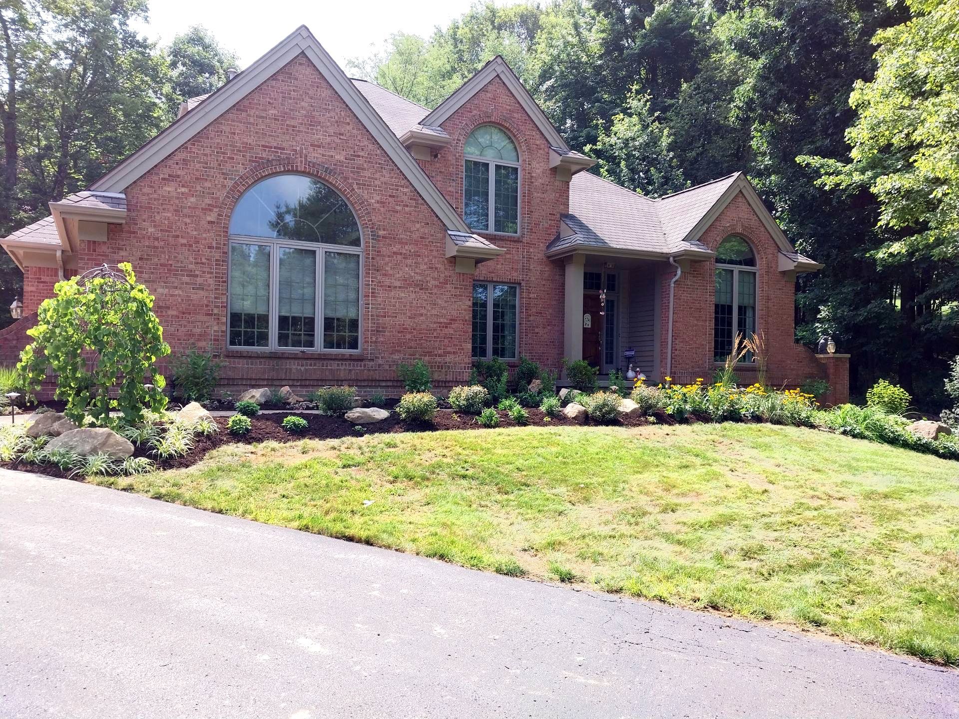 A large brick house with a lush green lawn in front of it