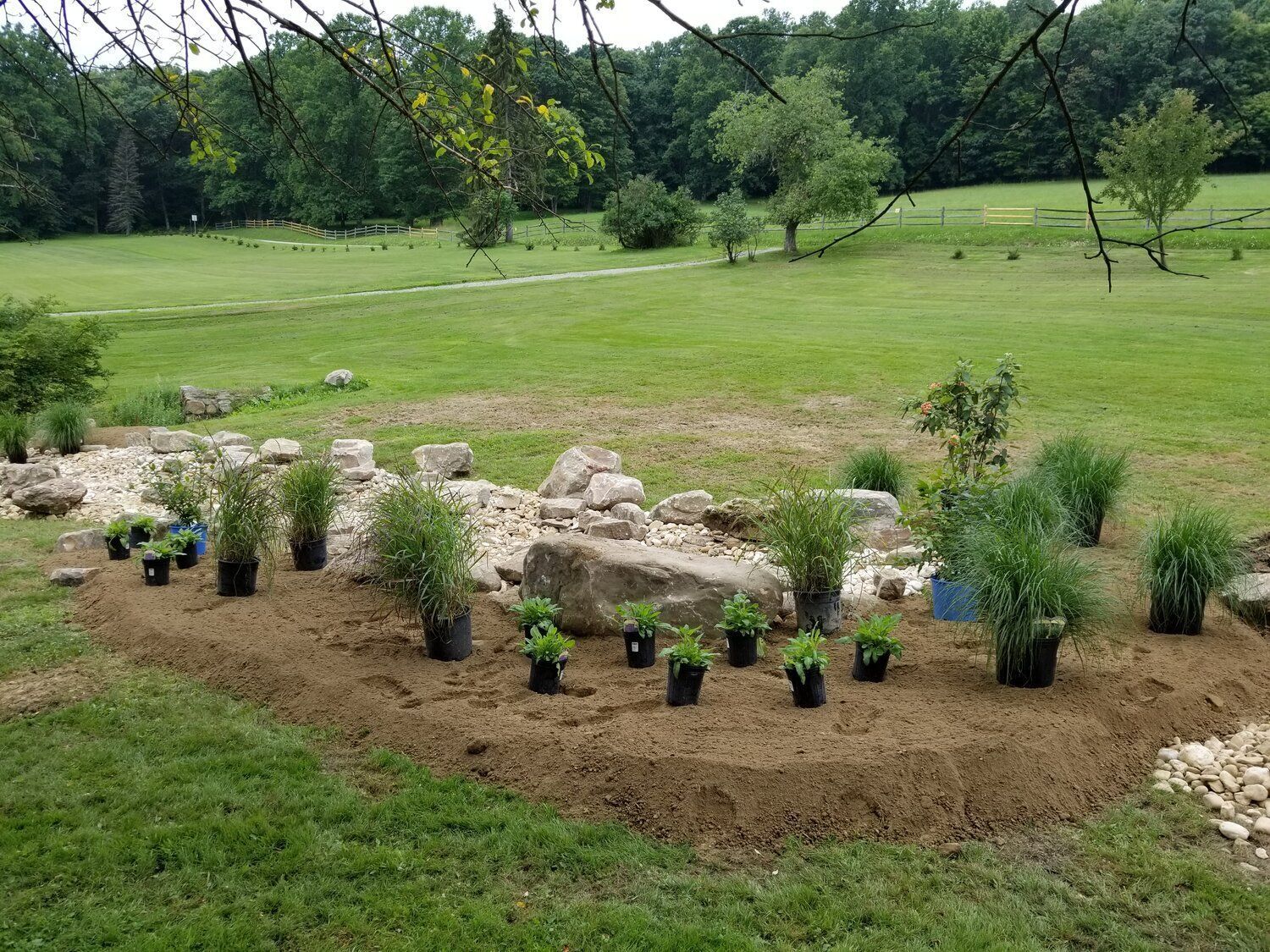 A garden with lots of potted plants and rocks in a field.
