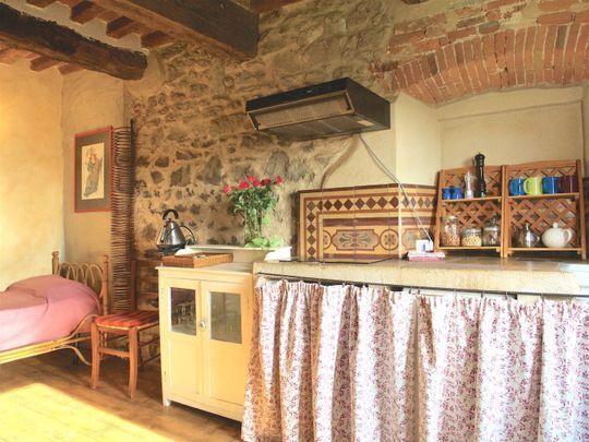 Luminoso soggiorno con letto aggiuntivo e interni in pietra a vista per una vacanza in agriturismo in Toscana.