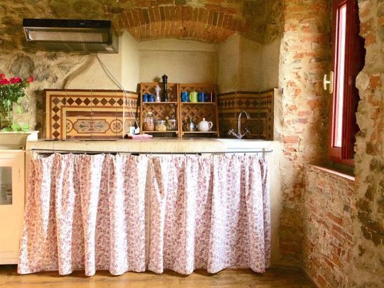 Luminoso soggiorno con letto aggiuntivo e interni in pietra a vista per una vacanza in agriturismo in Toscana.