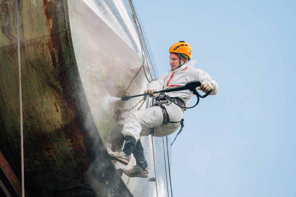 Industrial Climber Washing Big Barrel With Water Pressure — Barney’s Tank Cleaning in Morisset, NSW