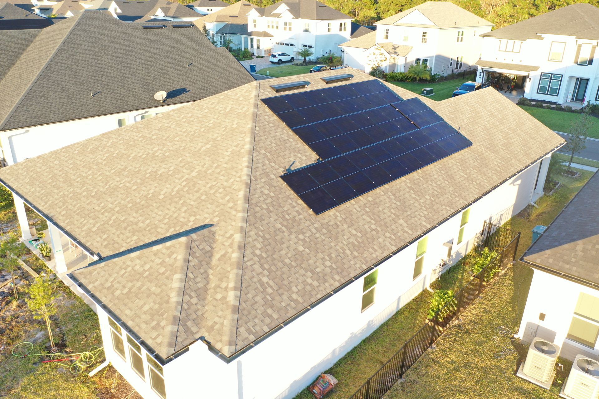 Aerial view of a suburban house with a large solar panel array on the roof.