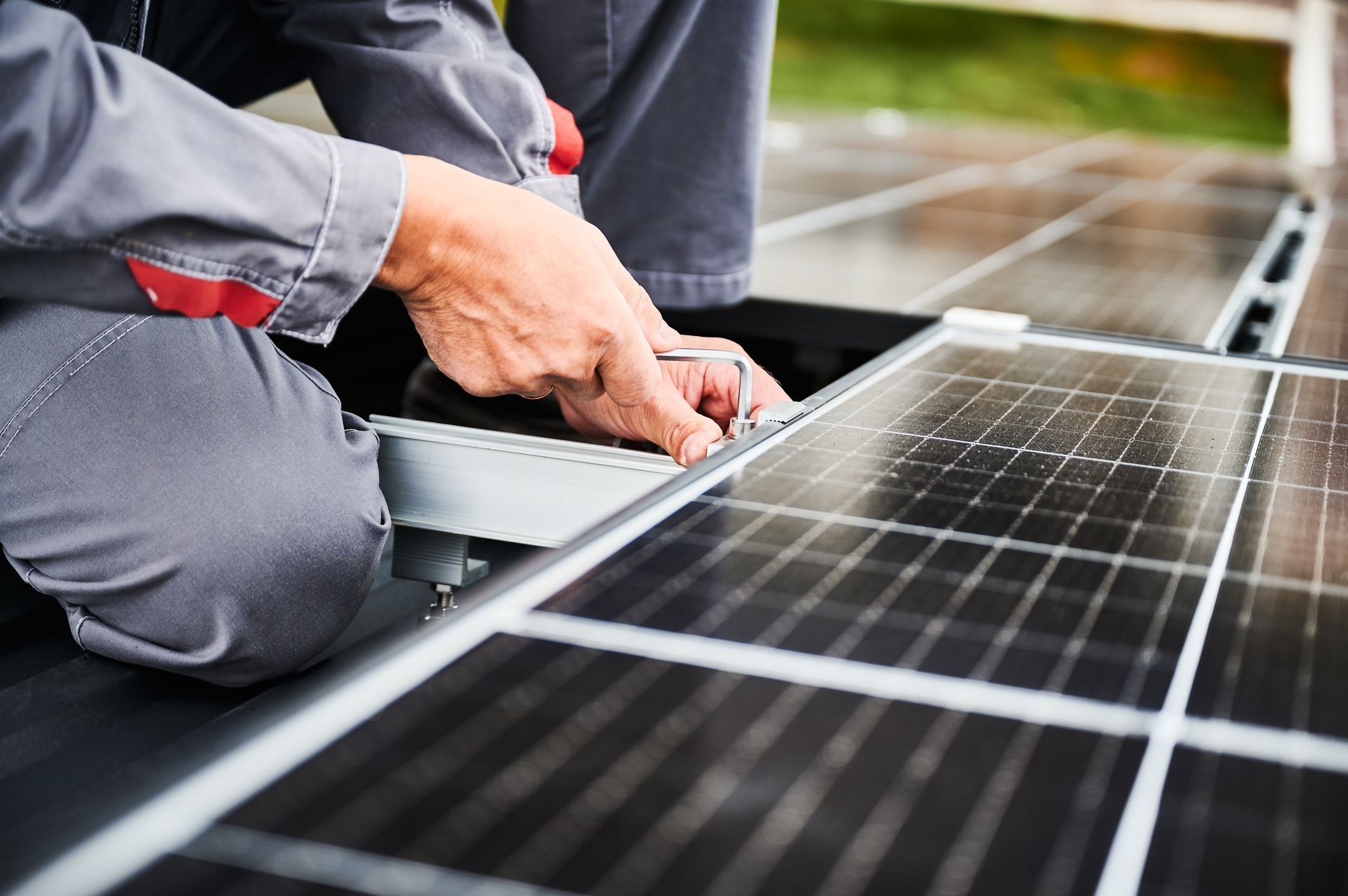 Technician installing solar panels on a rooftop, working with tools near black solar cells.