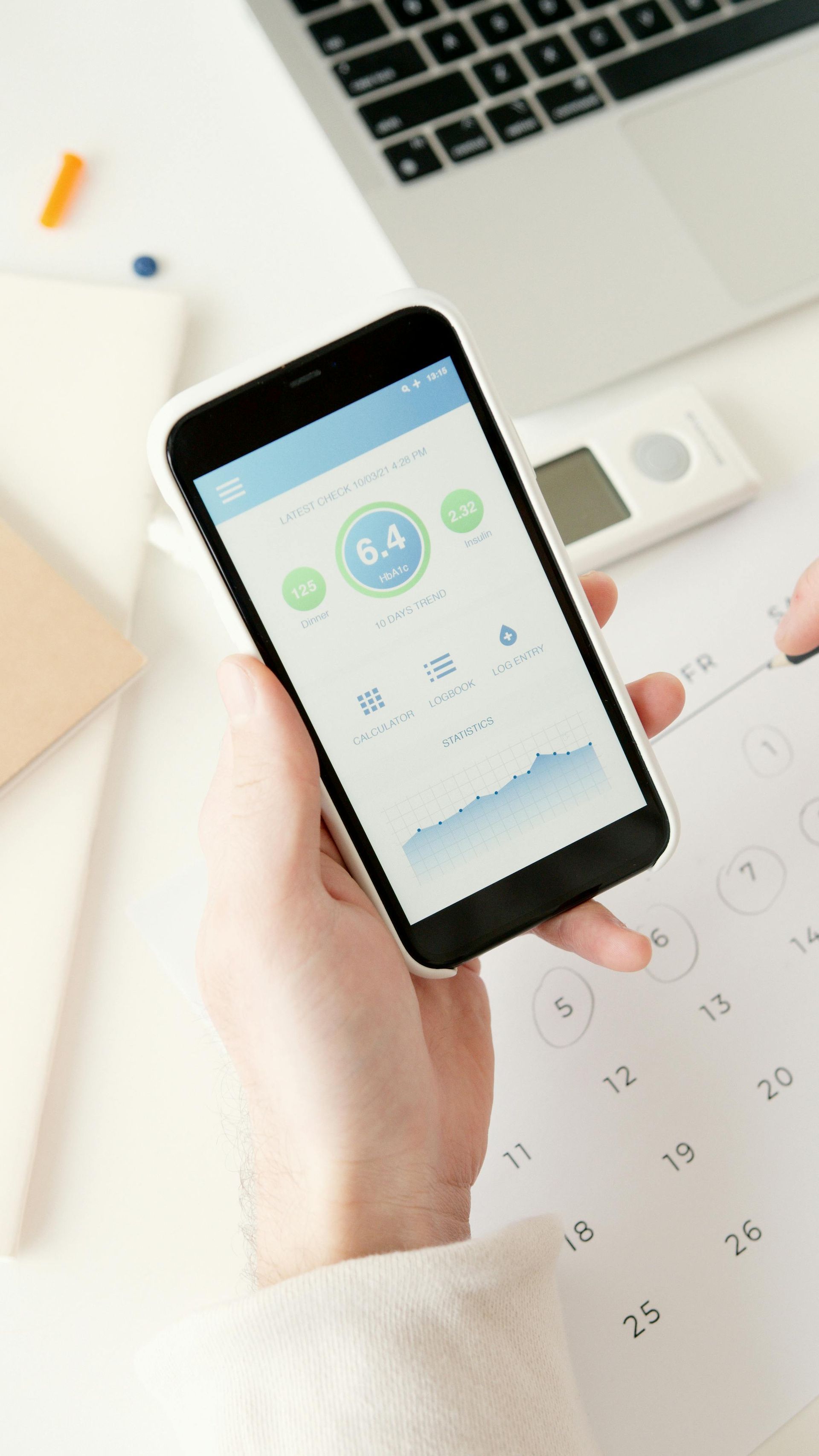 A person is holding a cell phone in front of a calendar.