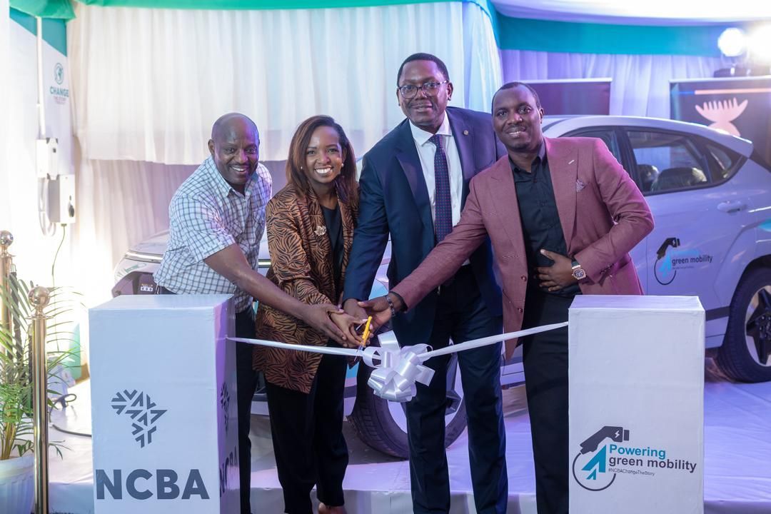 Four people cutting a ribbon near a car; promoting a bank.