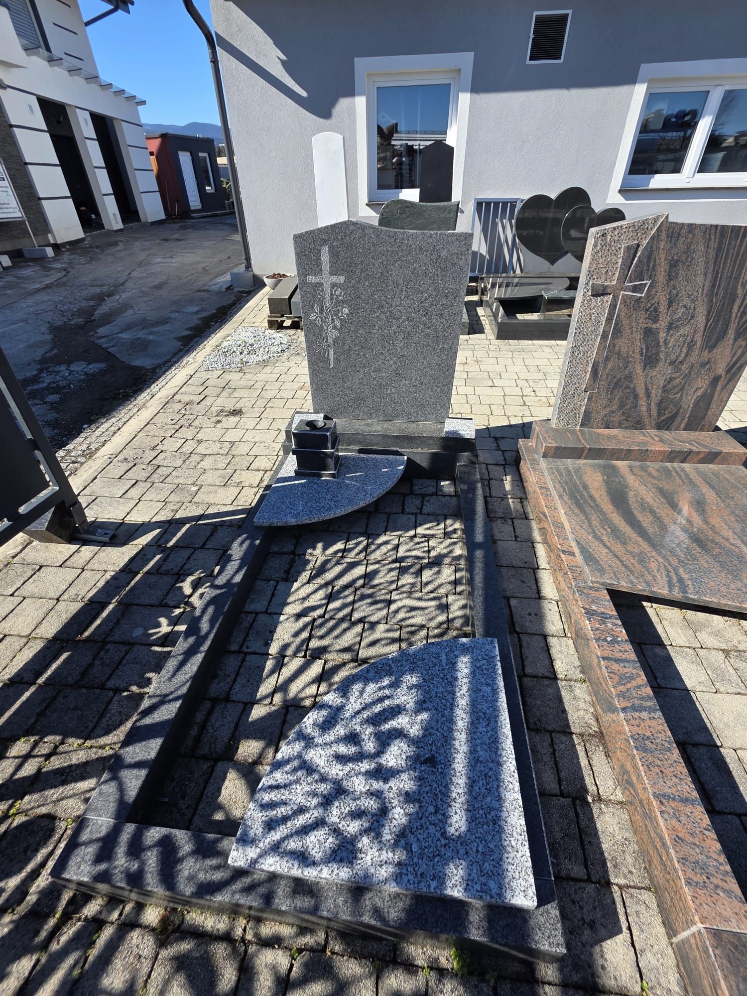 Terrasse im Freien mit Korbliegen, einem kleinen runden Tisch und einer weißen Gebäudewand im Sonnenlicht.