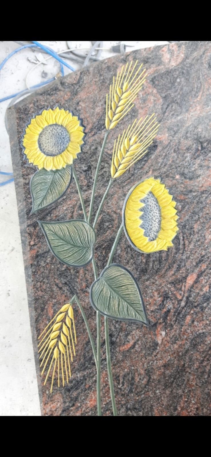 Handgefertigte Sonnenblumenstickerei mit gelben Blütenblättern und grünen Blättern auf dunklem Stoff, vertikal angeordnet