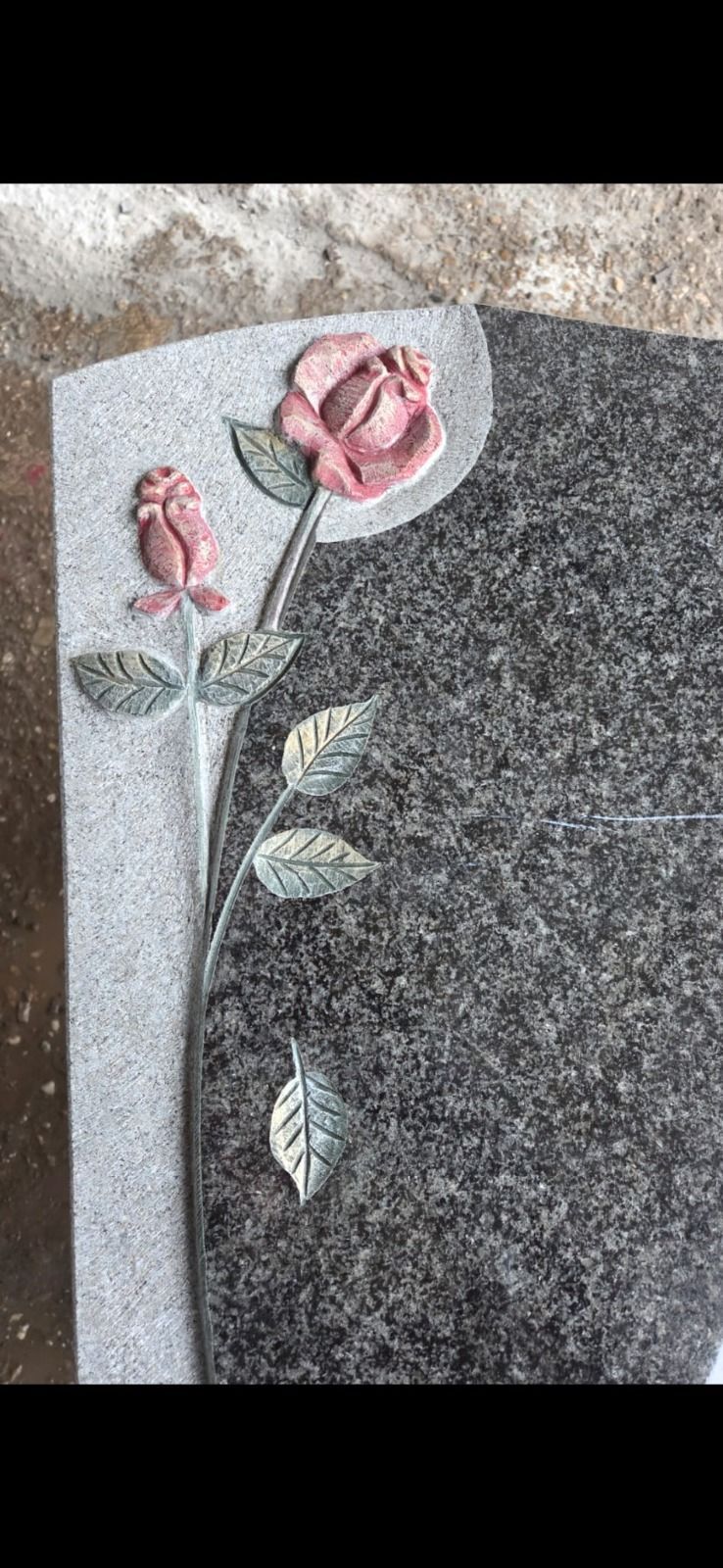 Rosa Rosenmuster auf grauem Granitgrabstein mit hellerer Steinumrandung
