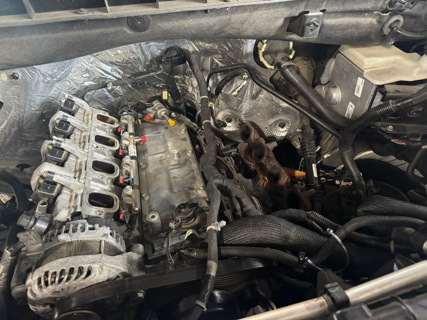Engine bay with exposed engine components, hoses, and wiring.