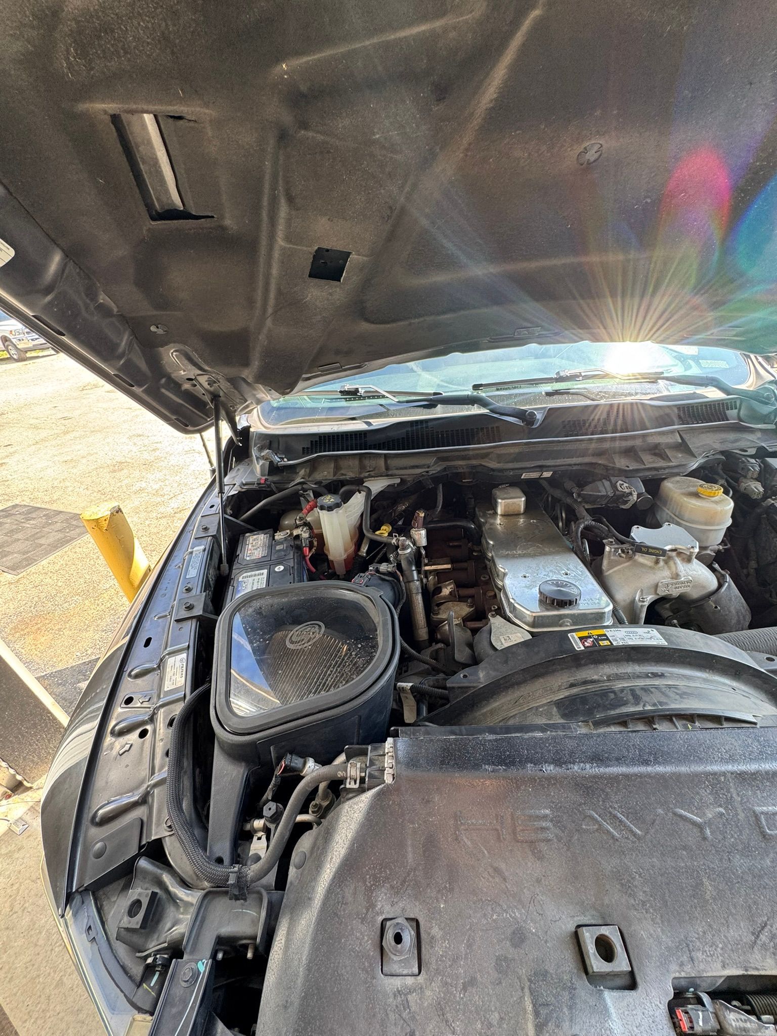 Open hood of a vehicle, revealing the engine compartment with various components.