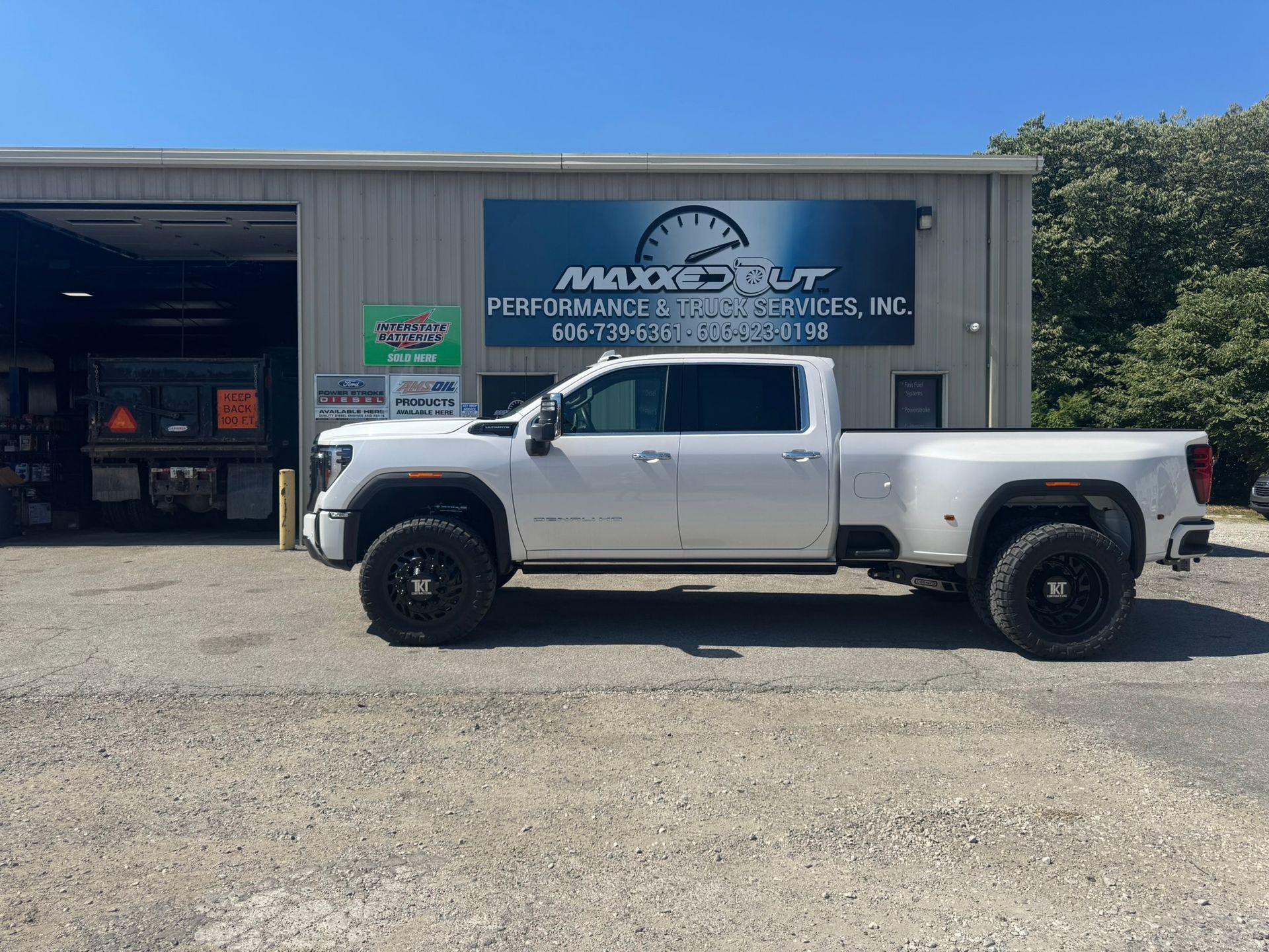 White pickup truck in front of a shop with a blue sign.
