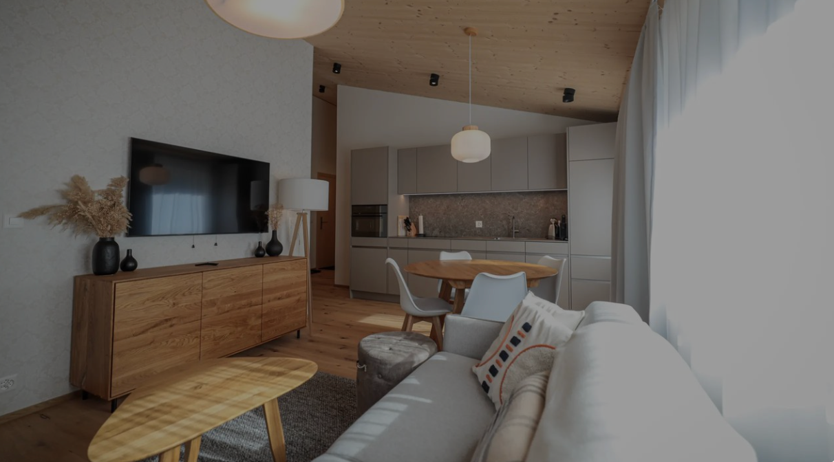 Modern living room with wood furniture, sofa, TV, and open kitchen with large windows