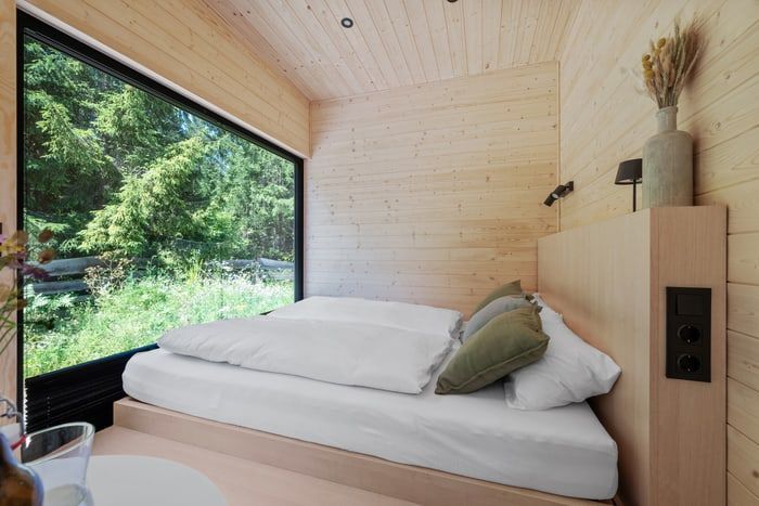 Minimal bedroom with a low bed beside a large window looking out to greenery