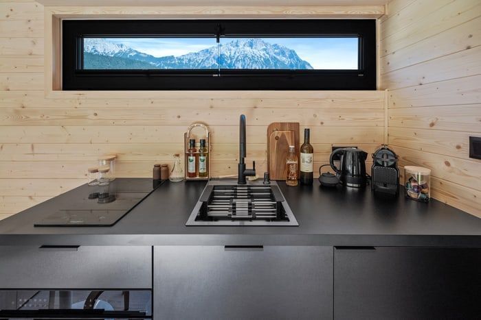 Modern minimalist kitchen counter with black appliances, gas stove, and mountain view window