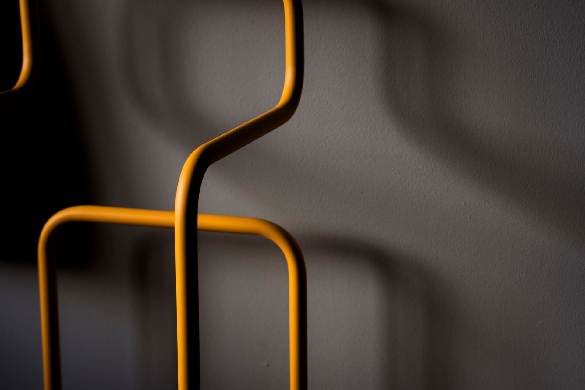 Modern hotel room with a white bed, striped curtains, chair, luggage rack, and abstract wall art.