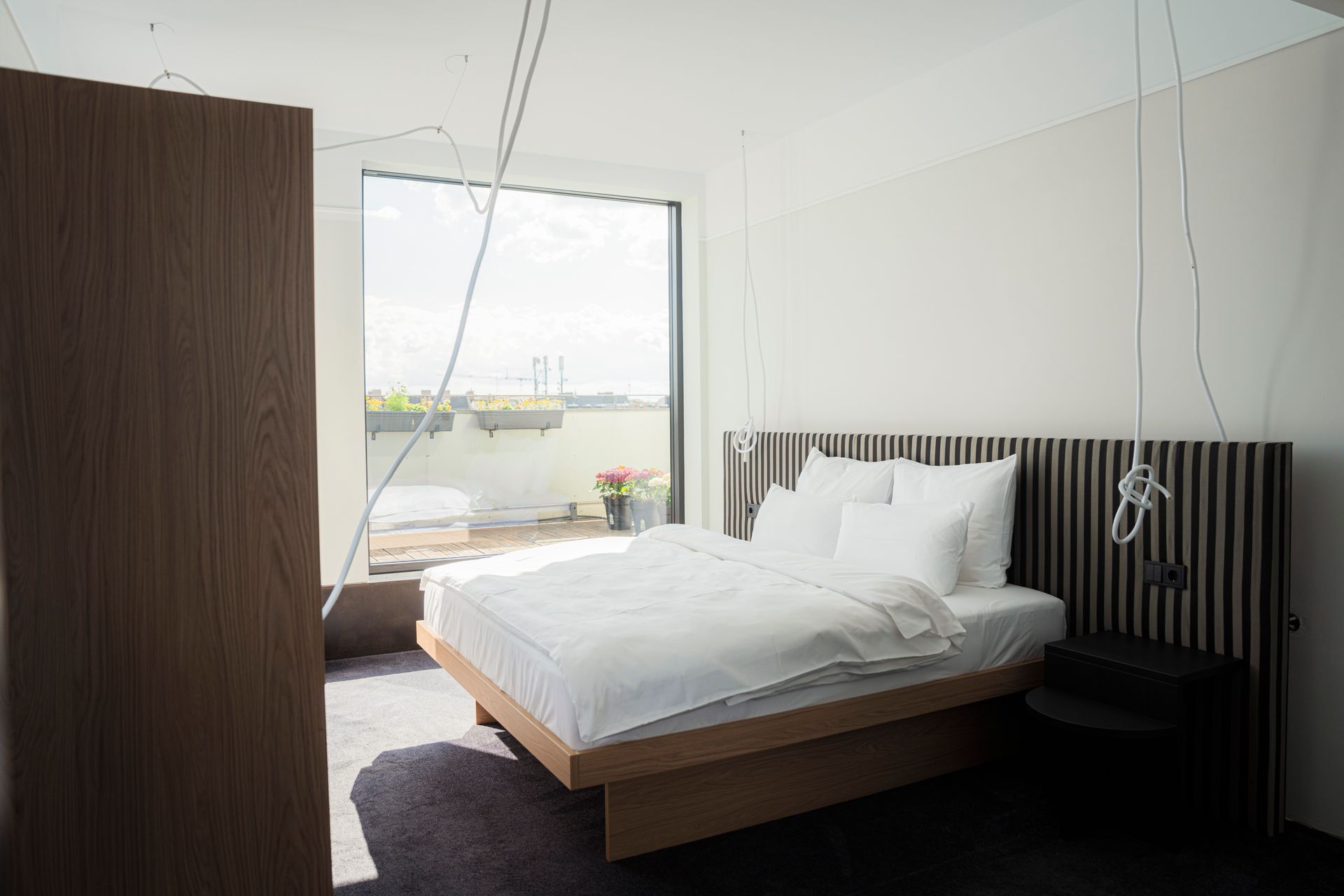 Modern bedroom with unmade bed, green curtains, and two brown chairs by a window