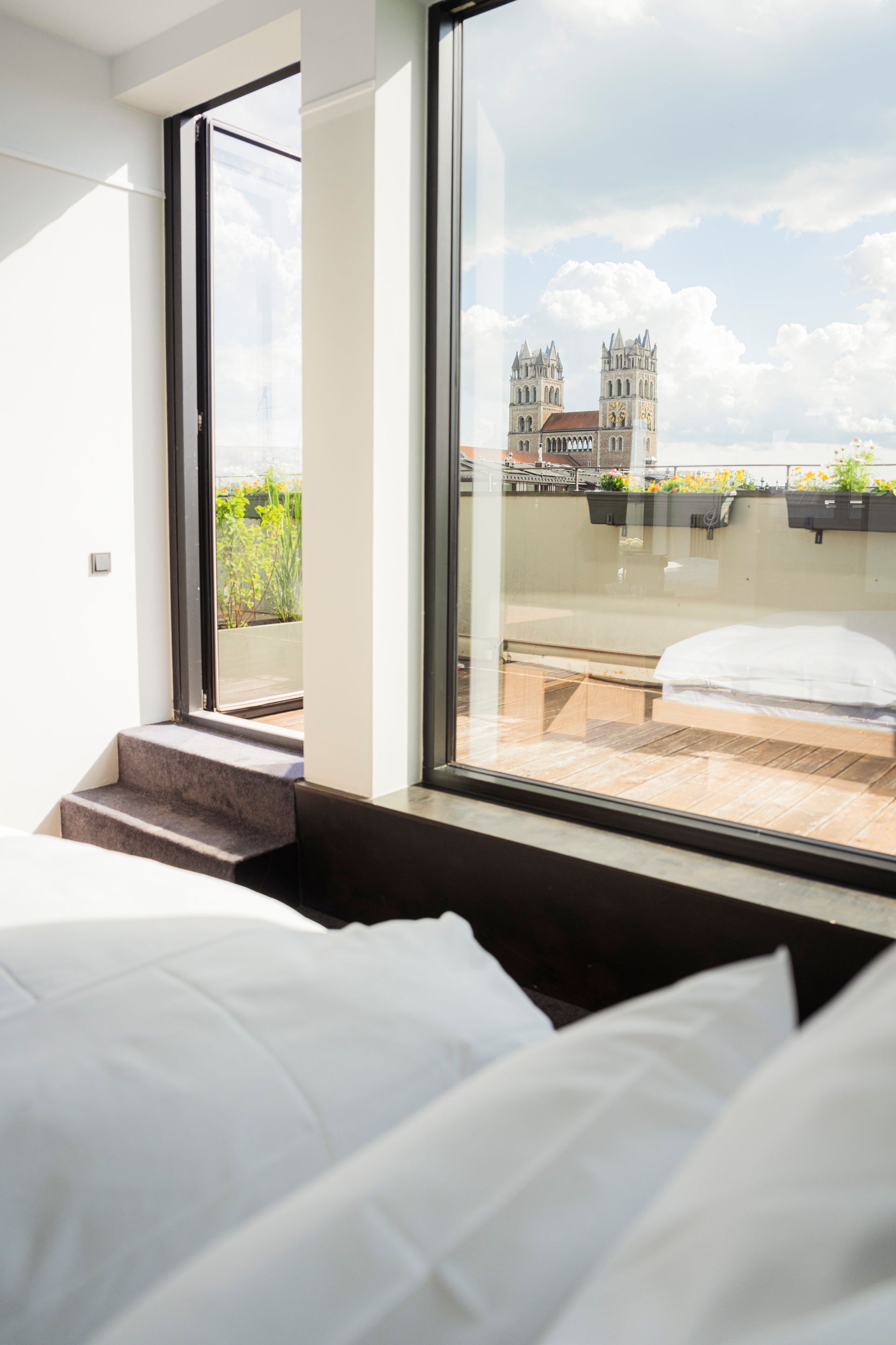 Bright bedroom with a white bed, striped headboard, wood floor, and abstract wall art in warm sunlight