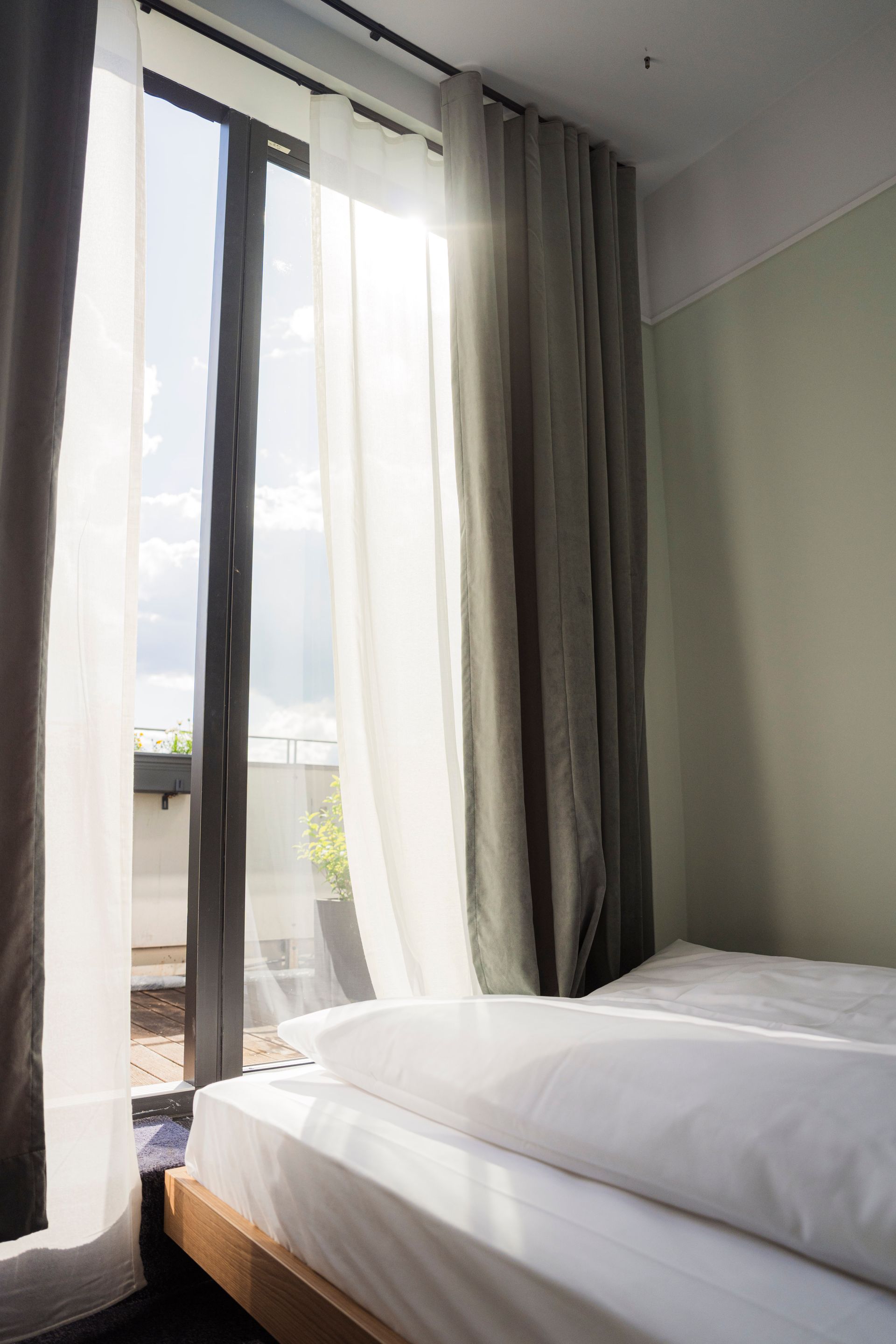 Modern hotel room with bed, wall-mounted TV, desk, lamp, and open closet.