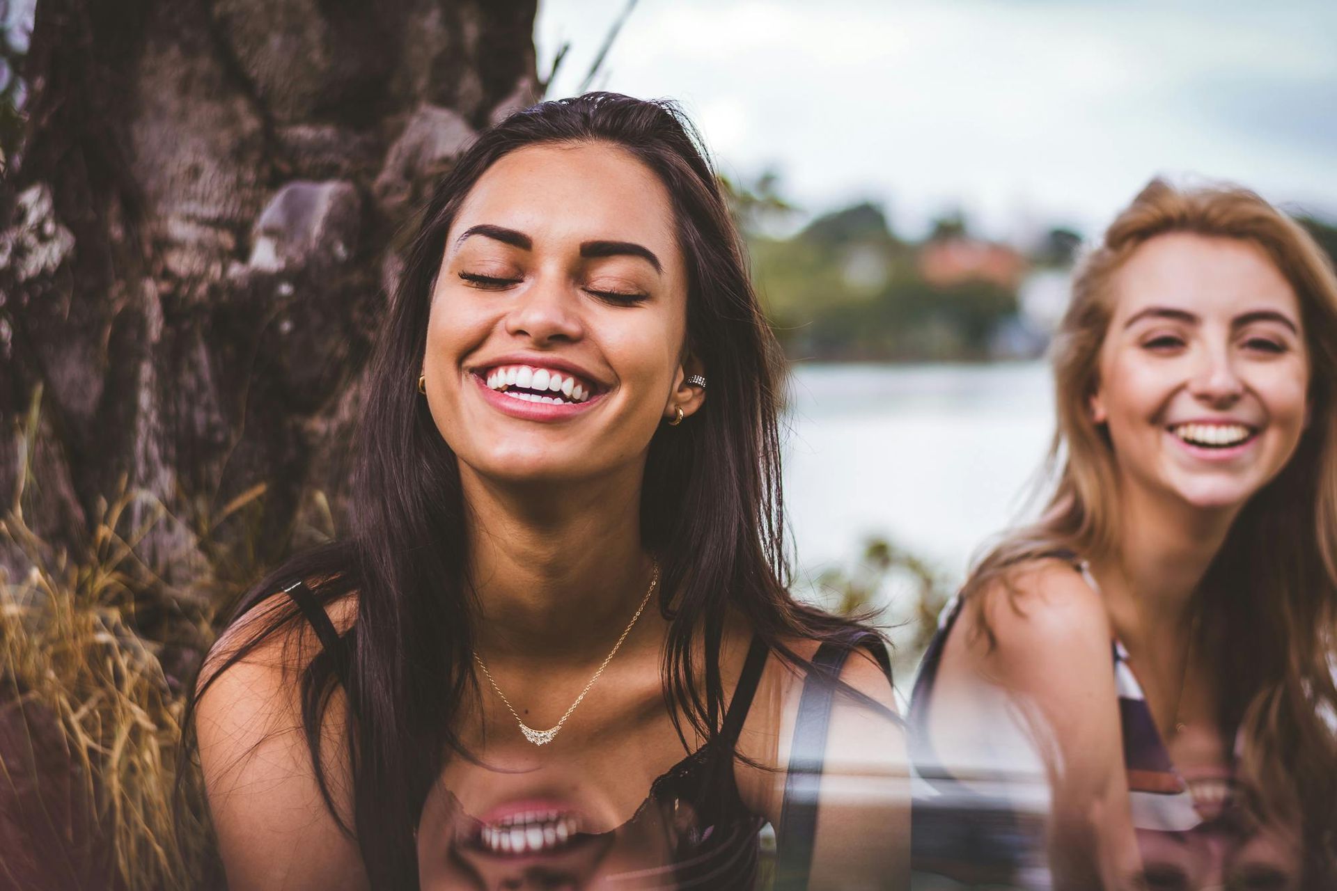 Two women are sitting next to each other and smiling. castellano payment plans 