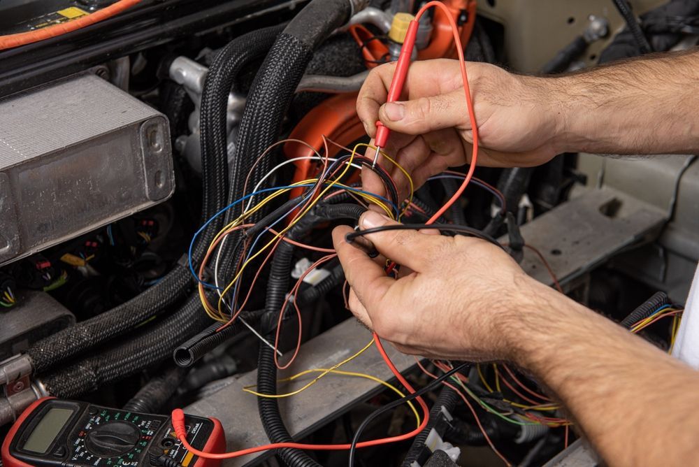 Hands Working With Tangled Wires Inside an Engine Compartment — Wingham Mechanical in Wingham, NSW