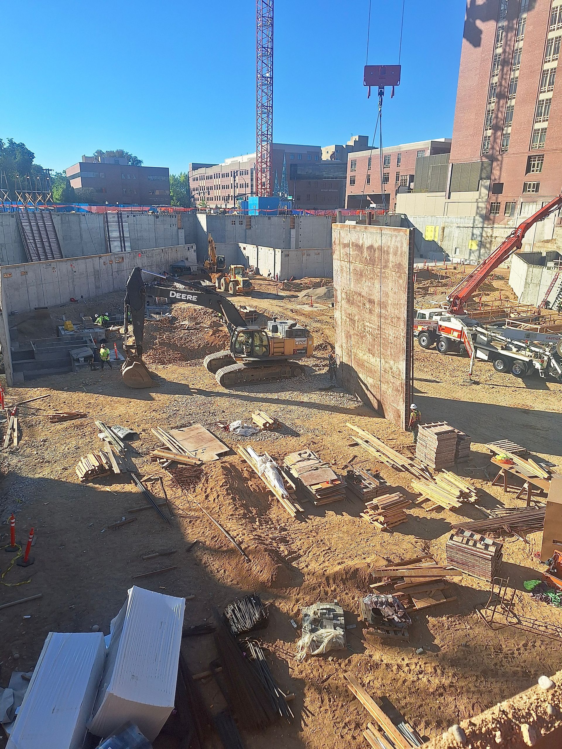 Construction site with crane, excavator, and partially built walls.