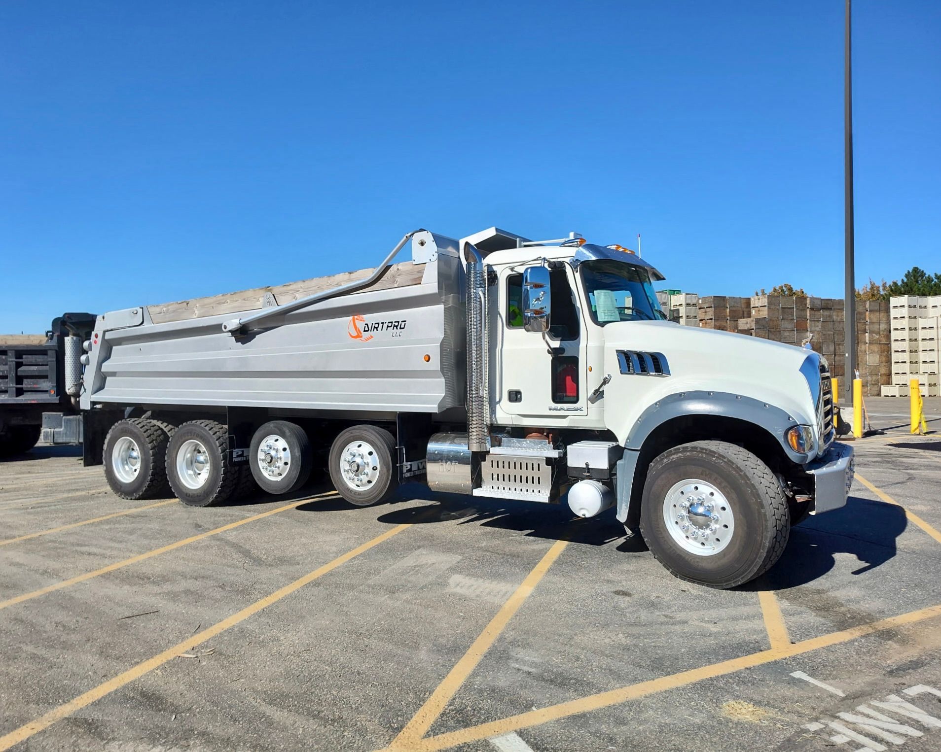 White dump truck parked on a paved lot on a sunny day.