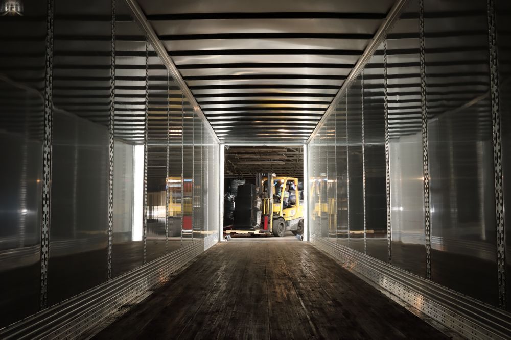 Empty metal shipping container interior with a forklift visible at the far end