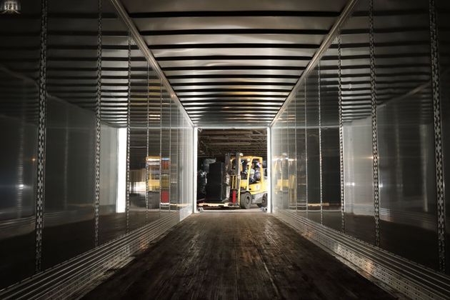 Empty metal shipping container interior with a forklift visible at the far end